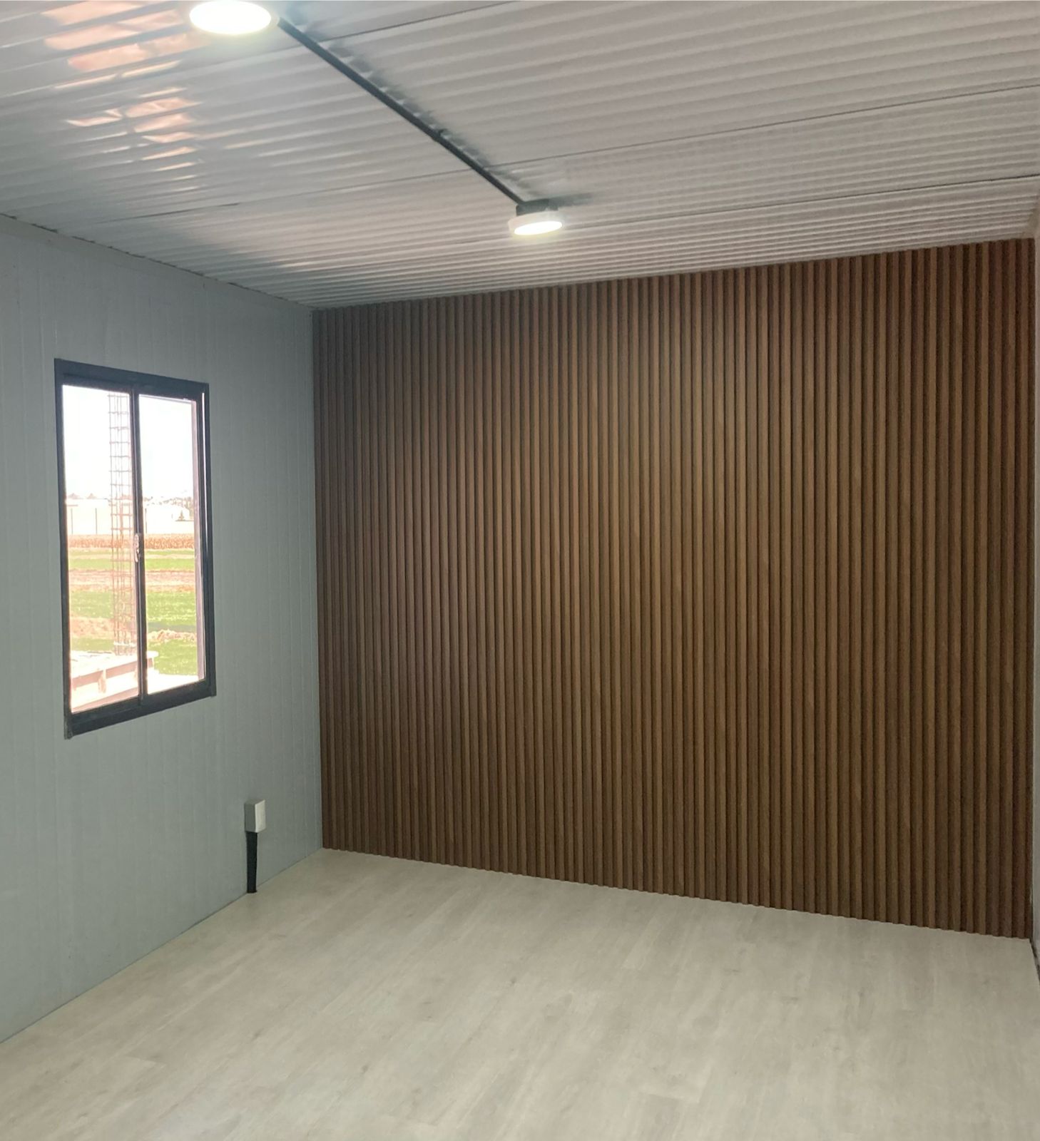 Interior de módulo terminado con muro de madera y ventana, listo para amueblar
